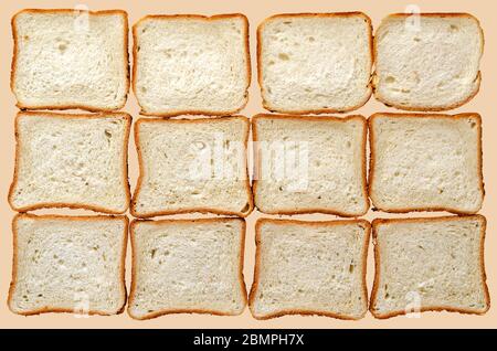 Toast bread background. Twelve slices of sliced bread on a light beige background. Rectangular slices of wheat bread. View from above. Stock Photo