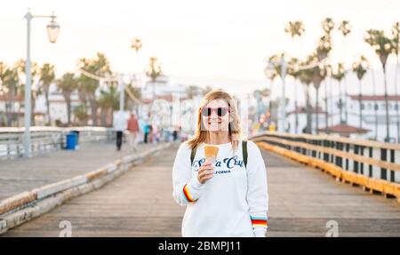 A woman eats ice cream on a pier at sunset Stock Photo