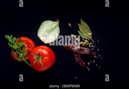 tomatoes, onions and spices on a black background Stock Photo