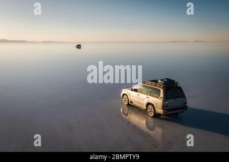 4WD vehicles exploring Uyuni Salt Flats (Spanish: Salar de Uyuni ) at sunrise in Bolivia, South America. Stock Photo