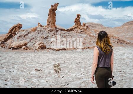 Female traveler at natural landmark Three Marias (Spanish: Las Tres Marias ) rock formation at the Moon Valley in the Atacama Desert, Chile. Stock Photo