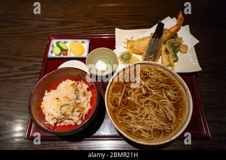 Japanese lunch, dinner meal of ramen soup in the bowl and rice on the side with tempura deep fried seafood, vegetables and sauces. Japanese food Stock Photo
