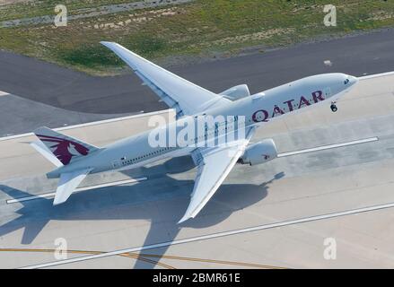Qatar Airways Boeing 777 departing LAX International Airport runway. Aerial view of B777 jet taking off from a high angle to Doha, Qatar. Stock Photo