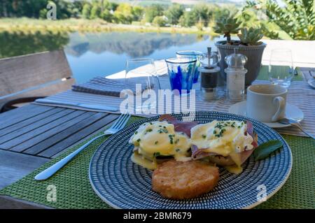 Eggs Benedict with Hollandaise and hash browns served on a plate outside Stock Photo