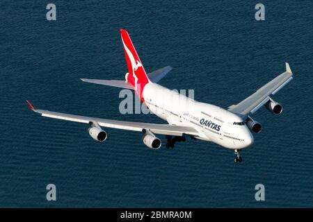 Qantas Airways Boeing 747 on final approach to Sydney International Airport over Botany Bay waters. Jumbo 747-400 VH-OJS aircraft retired aerial view. Stock Photo