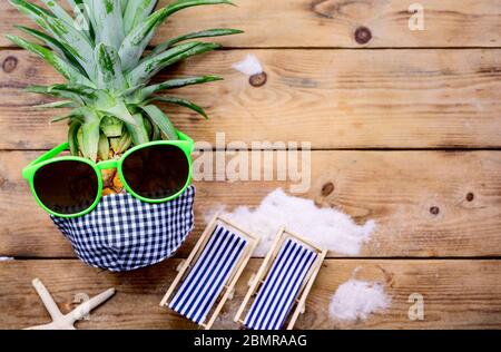 Pineapple with sunglasses on wood background. Creative minimal summer holiday concept with miniature toy. Stock Photo