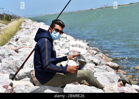 Man fishing at the beach wearing a face mask Stock Photo - Alamy