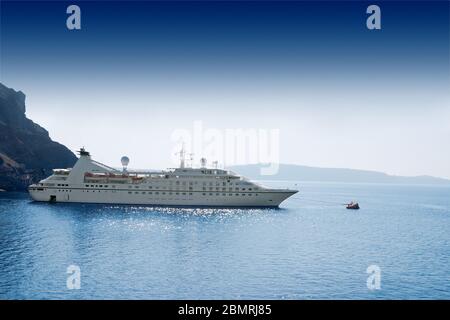 luxury white cruise ship on a clear day with calm seas and blue sky on the greek island of santorini Stock Photo