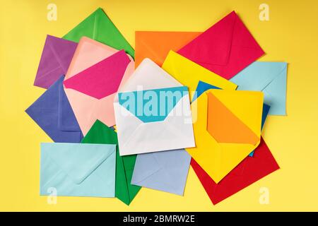 C6 envelopes of various colors, shot from the top on a yellow background Stock Photo