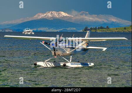 Cessna float plane approaching its mooring on Lake Taupo, in the north island of New Zealand. The active cones of the volcanoes are in the background. Stock Photo