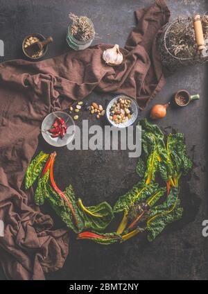 Food background with fresh colorful chard leaves on dark rustic table  background with herbs and spices. Top view. Circle frame. Country style. Clean Stock Photo