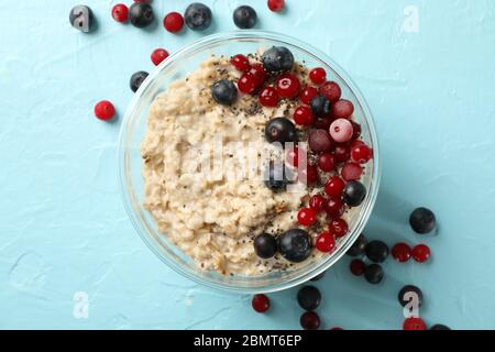 Bowl with oatmeal porridge and fruits on blue background Stock Photo