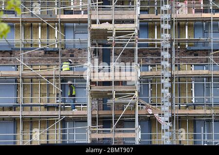 Ashford, Kent, UK. 11 May, 2020. Coronavirus update: Following the announcement by the government that workers who cannot work from home can go back to work, construction workers on a large building site in the city centre are seen busy at work. Two builders are seen busy at work high up on scaffolding. Photo Credit: Paul Lawrenson/Alamy Live News Stock Photo
