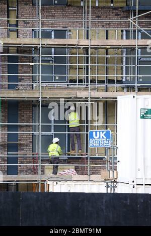 Ashford, Kent, UK. 11 May, 2020. Coronavirus update, following the announcement by the government that workers who cannot work from home can go back to work construction workers on a large building site in the city centre are busy at work. Two builders are seen busy at work high up on scaffolding. ©Paul Lawrenson 2020, Photo Credit: Paul Lawrenson/Alamy Live News Stock Photo