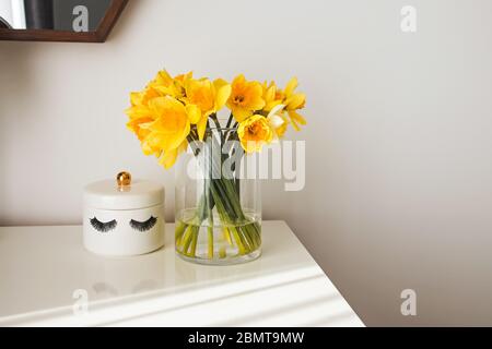 Modern minimalist white room interior with yellow flowers satnding on the table in natural sunlight from the window Stock Photo