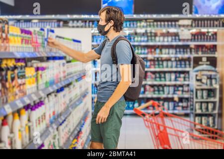 Alarmed man wears medical mask against coronavirus while purchase of household chemicals in supermarket or store- health, safety and pandemic concept Stock Photo