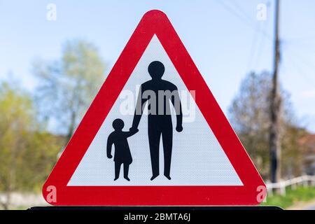 Macro close up Highway Code red triangle road sign warning of pedestrians walking, UK Stock Photo