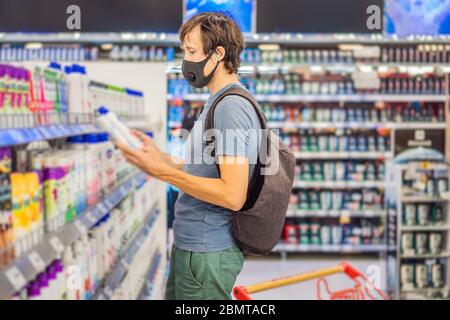 Alarmed man wears medical mask against coronavirus while purchase of household chemicals in supermarket or store- health, safety and pandemic concept Stock Photo