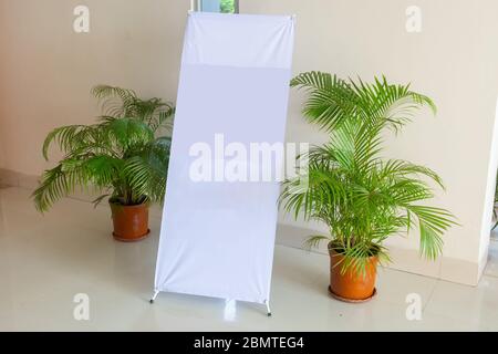 A white blank design displays X-Stand on an indoor wall side. A Blank Banner Design display X-Stand Mockup. Template Mockup for your content and design Stock Photo
