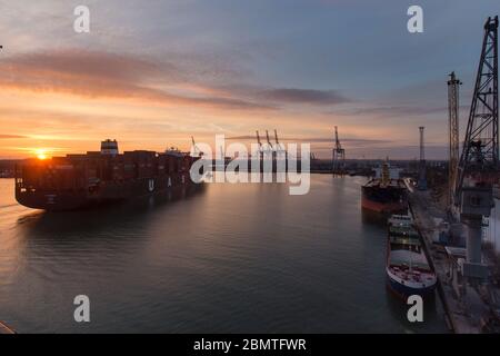 City of Southampton, England. Picturesque sunset view of a container ship navigating the River Test at Southampton Docks. Stock Photo