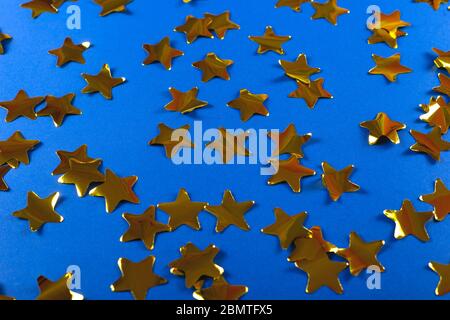 Gold confetti made from stars on blue. Bright festive pattern Stock Photo