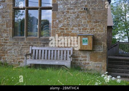 Defibrillators housed in a wooden case attached to the wall of the village hall in the north Oxfordshire village of Swerford Stock Photo