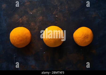 Three oranges on a dark background. Citrus on the table Stock Photo