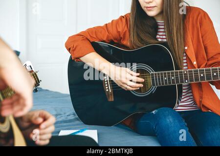 Learning to play the guitar. The teacher explains to the student the basics of playing the guitar. Individual home schooling or extracurricular lessons. Stock Photo