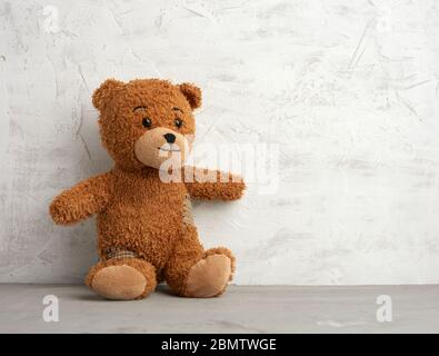 brown teddy bear with patches sits on a white background, place for an inscription Stock Photo