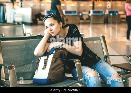 Upset or bored girl tourist or student at the airport. Her flight was delayed or she was tired. Stock Photo