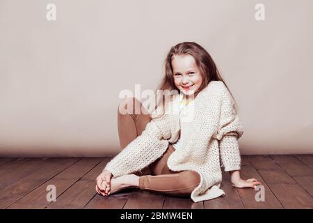 Cute little girl sitting on white carpet and smiling at camera Stock Photo  - Alamy