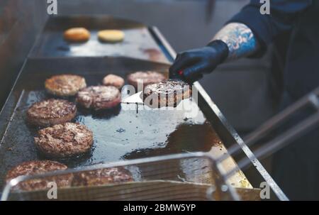 Chef cooking hamburgers.Professional cook frying beef meat on pan in restaurant kitchen.Worker cooking burgers.Kitchen employee preparing pork cutlets Stock Photo
