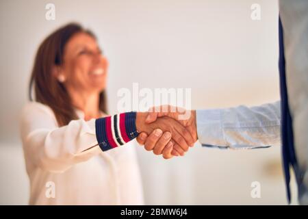 Two middle age business workers smiling happy and confident. Working together with smile on face doing handsake at the office Stock Photo