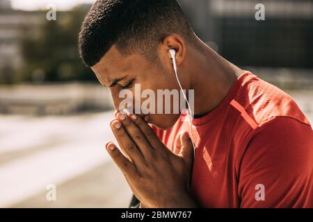 Sportsman with earphones concentrating before exercising outdoors. fitness man getting ready before workout in the city. Stock Photo