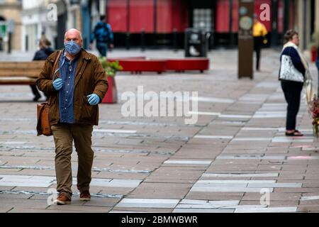 A man wearing a protective face mask walks through the centre of Bath, Somerset, as the UK government lockdown restrictions start to be eased. Stock Photo