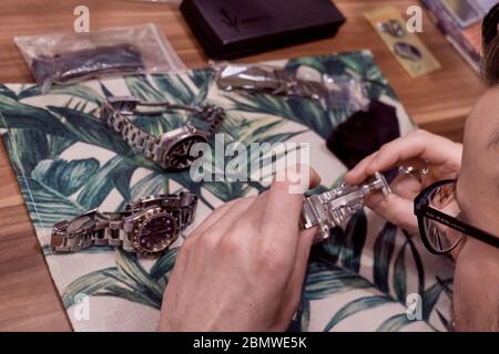 The hands of a watchmaker repairing a mechanical watch. Tools for repairing mechanical watches. repairing wrist watch. Selective focus. Stock Photo