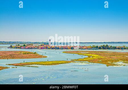 Aerial panoramic view of Venetian Lagoon with Burano island, water canals and swamp. View from bell tower of Torcello island. Veneto Region, Northern Italy. Blue cloudy sky background. Stock Photo