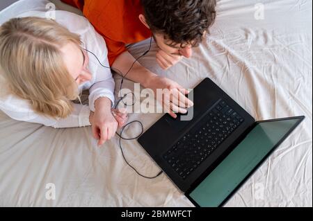 Smiling young adult couple using laptop and headphones together top view Stock Photo