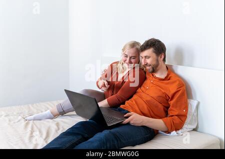 Smiling young adult couple using laptop and laughing together Stock Photo