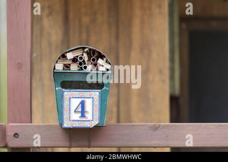 An old home letterbox now attached to a backyard cubby house and converted to a bug or bee or insect hotel using scrap timber and bamboo cuttings Stock Photo