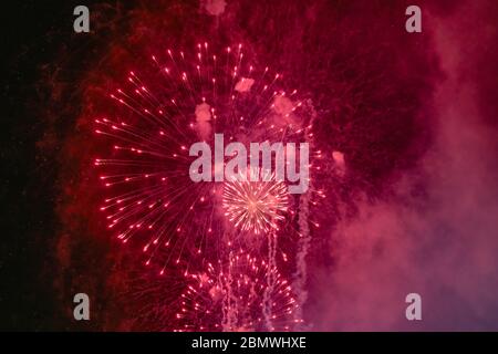 Red firework with smoke over the black sky. Low key exposure. Stock Photo