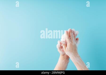 Hands of a child in soapy antibacterial foam, on a blue background, top view. Minimalistic concept of free space. Stock Photo