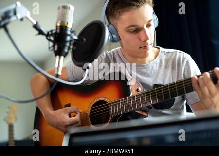 Teenage Boy Playing Guitar And Recording Music At Home Stock Photo