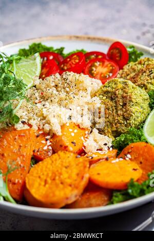 Vegan dinner. Quinoa salad with baked sweet potato, falafel, kale and pea seedlings. Healthy vegetarian buddha bowl. Falafel salad bowl. Stock Photo