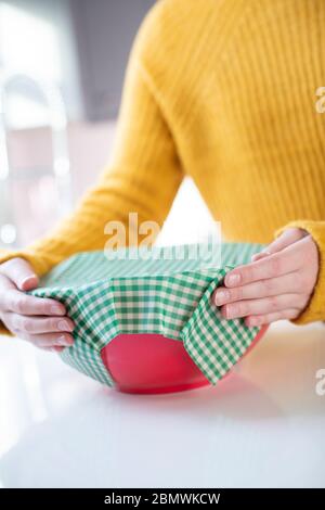 Close Up Of Woman Wrapping Food Bowl In Reusable Environmentally Friendly Beeswax Wrap Stock Photo