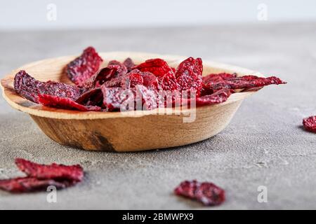Diet healthy eating concept. Dried beet chips or baked beets in a wooden bowl, on a gray concrete background. Organic natural food. Copy space. Stock Photo