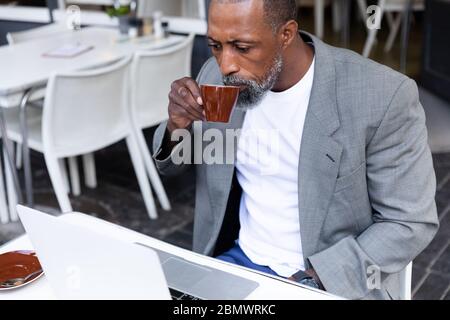 African American man working on his laptop at coffee terrace Stock Photo