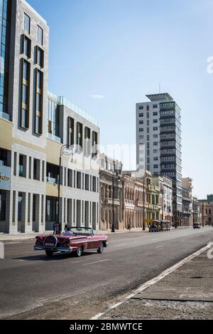 Classic car driving along the Malecon or Avenida de Maceo, a broad esplanade and road that stretches for 8 km along the coast, Havana, Cuba
