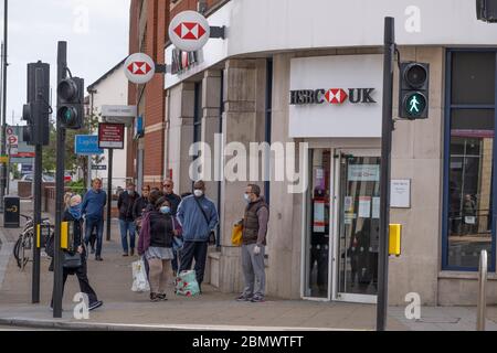 Wimbledon, London, UK. 11 May 2020. Socially distanced customers, some wearing face masks, queue outside a bank in the centre of Wimbledon waiting for access. Credit: Malcolm Park/Alamy Live News. Stock Photo