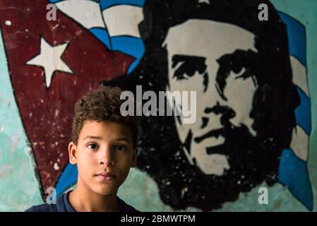 Boy next to Che Guevara wall painting , Old City Centre, Havana Vieja, Havana, Cuba Stock Photo